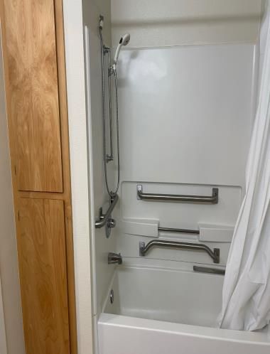 A bathroom with a bathtub , shower , and wooden cabinet.