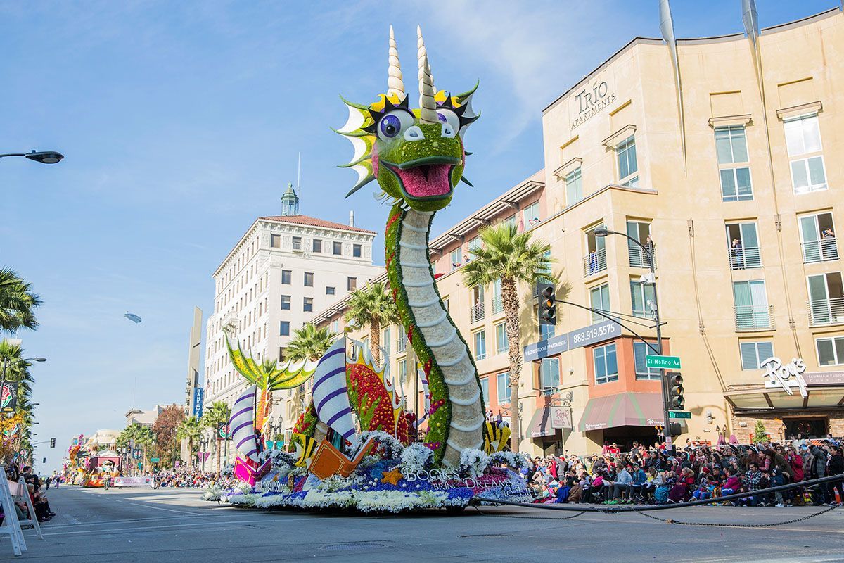 Dragon float in parade, green and colorful, with spectators lining the street.