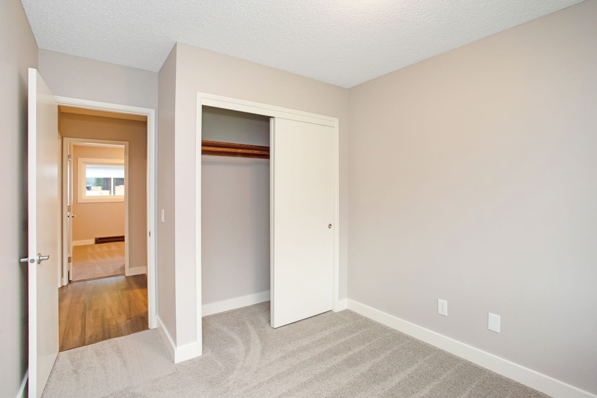 An empty bedroom with a closet and a carpeted floor