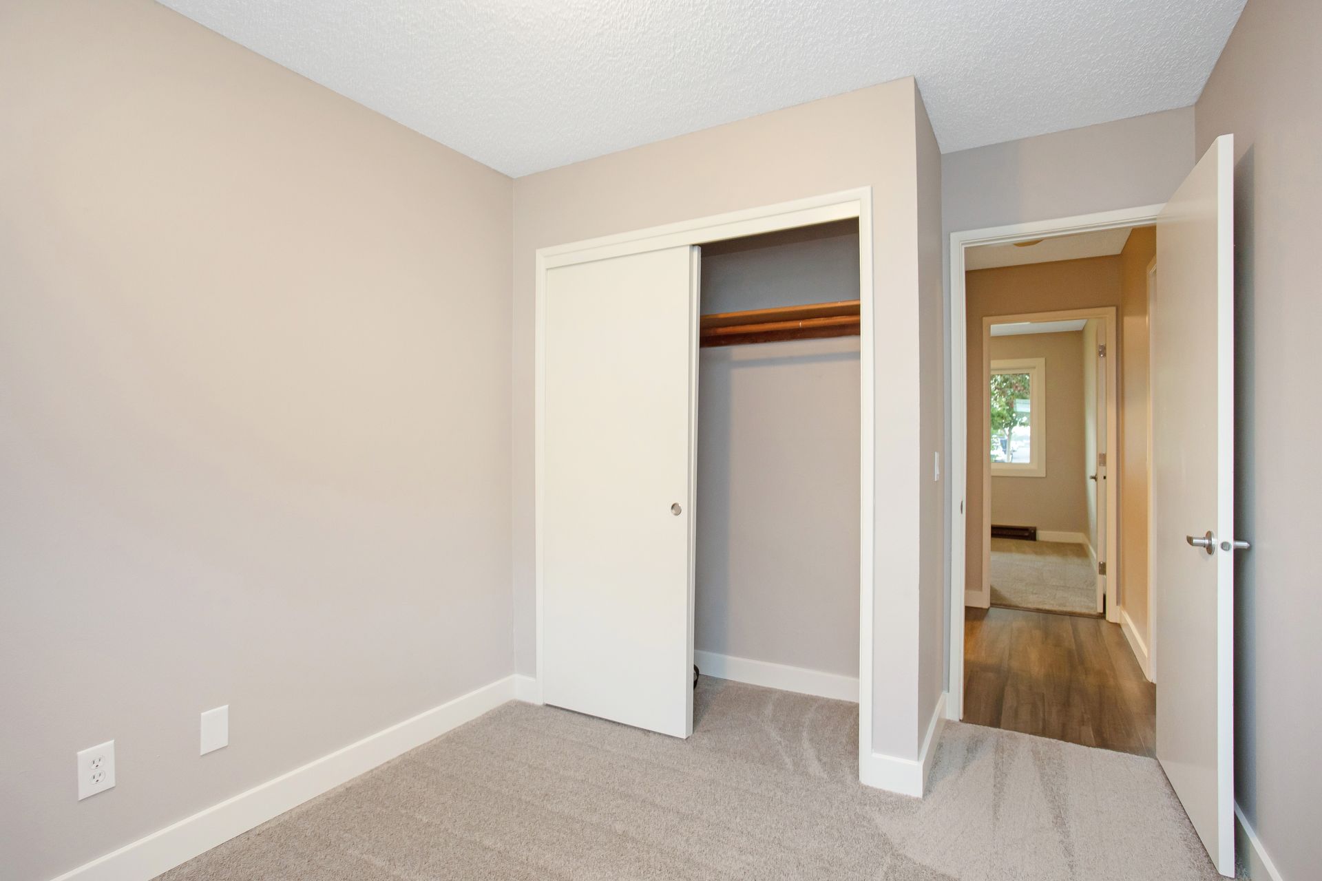 An empty bedroom with a closet and a window