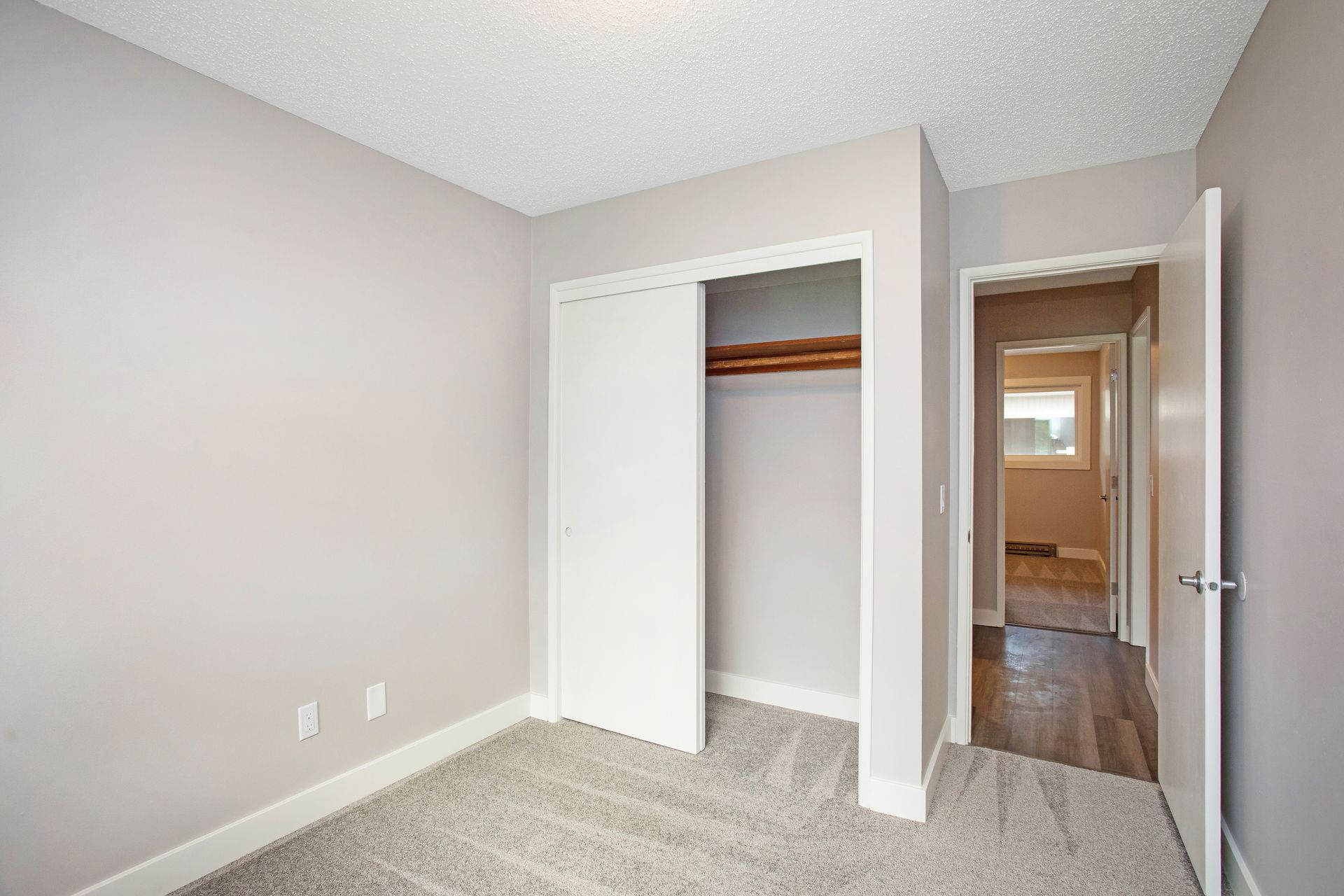 An empty bedroom with a closet and a hallway.