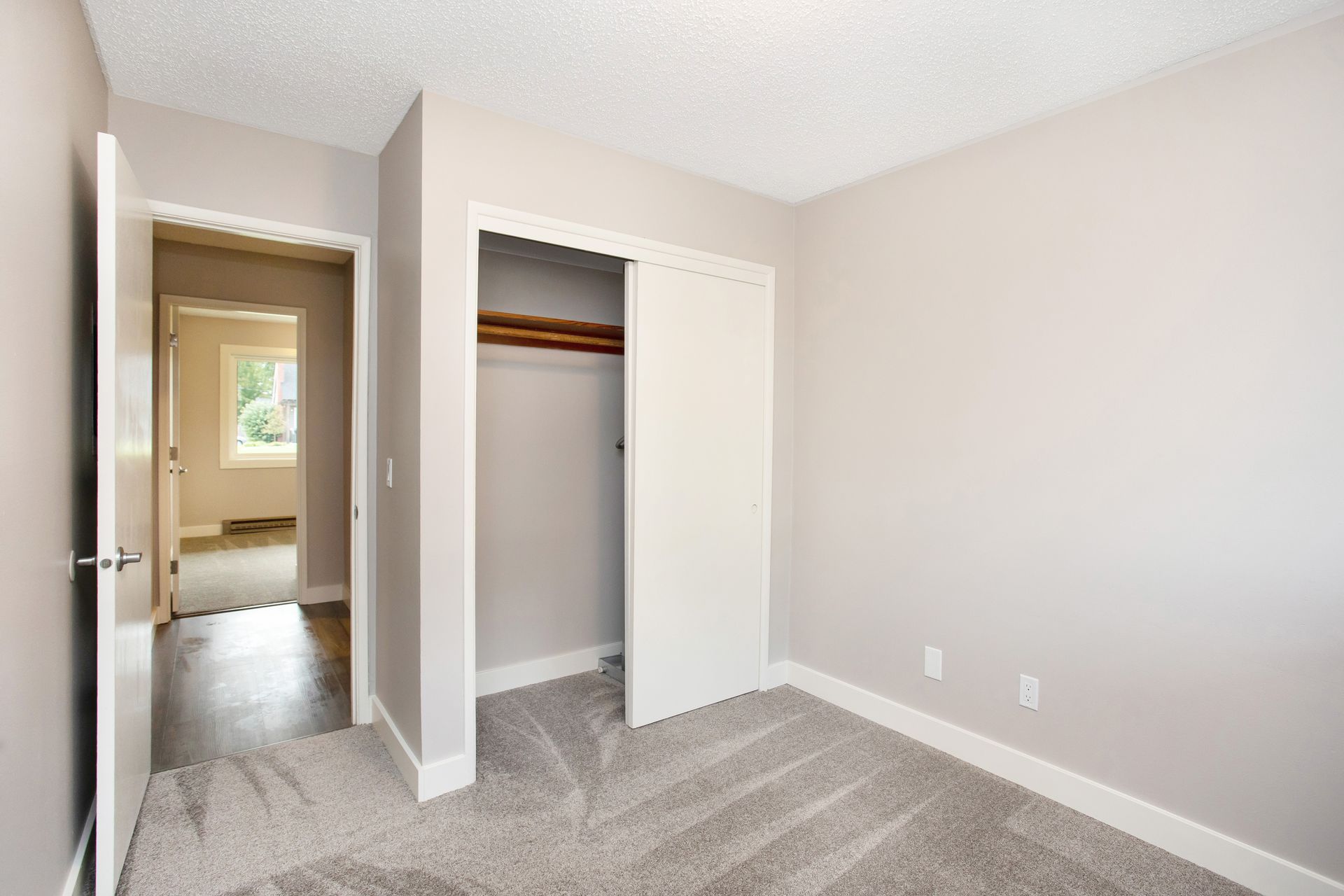 An empty bedroom with a closet and a window