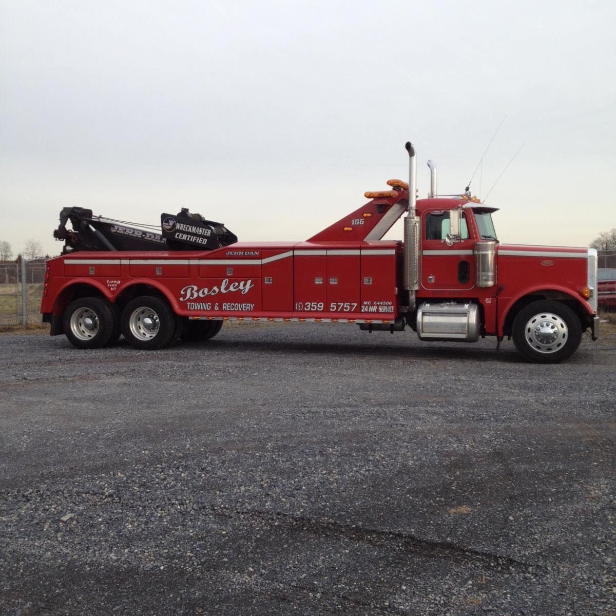 A tow truck is towing a car on the side of the road.