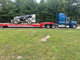 A blue and white tow truck is driving down a highway.