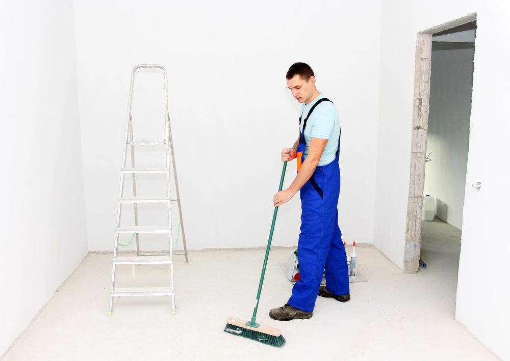 Man in Blue Overalls Sweeping Floor With Green Broom — Cleaners in Tamworth, NSW