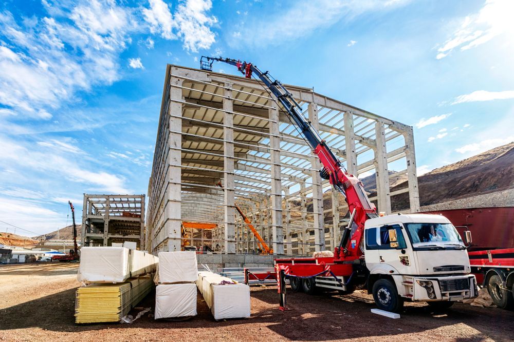 A Truck with A Crane Attached to It Is Parked in Front of A Building Under Construction — AMAC Cranes in Coolum Beach, QLD