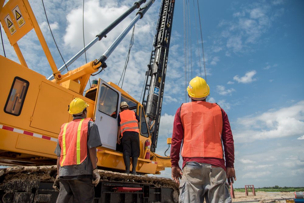 A Group of Construction Workers Are Standing in Front of A Crane — AMAC Cranes in Coolum Beach, QLD