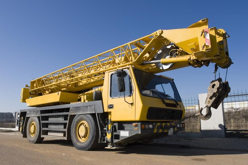 A Yellow Truck with A Crane Attached to It Is Parked on The Side of The Road — AMAC Cranes in Coolum Beach, QLD