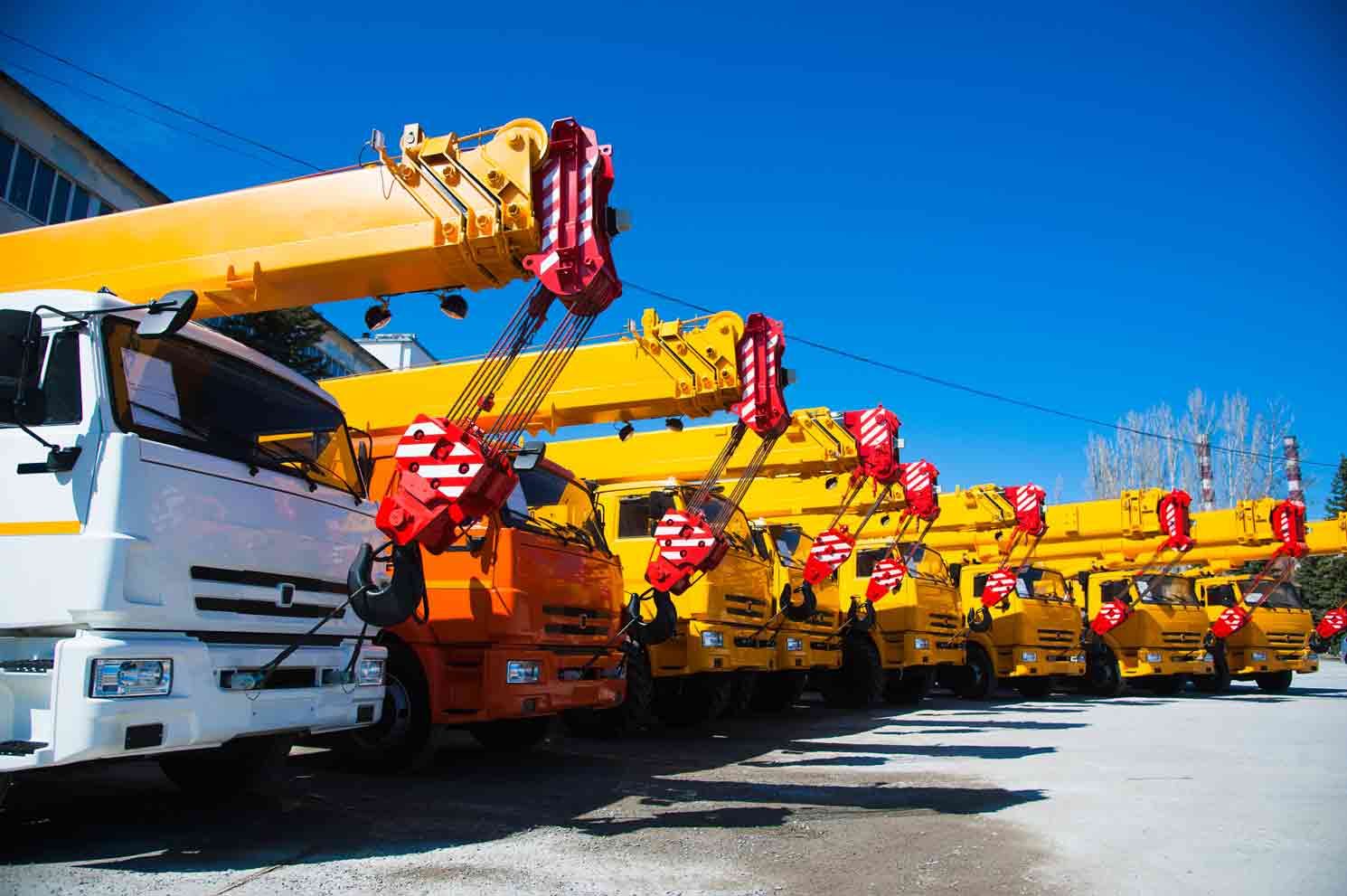 A Row of Yellow Trucks with Cranes on Them Are Parked in A Parking Lot — AMAC Cranes in Coolum Beach, QLD