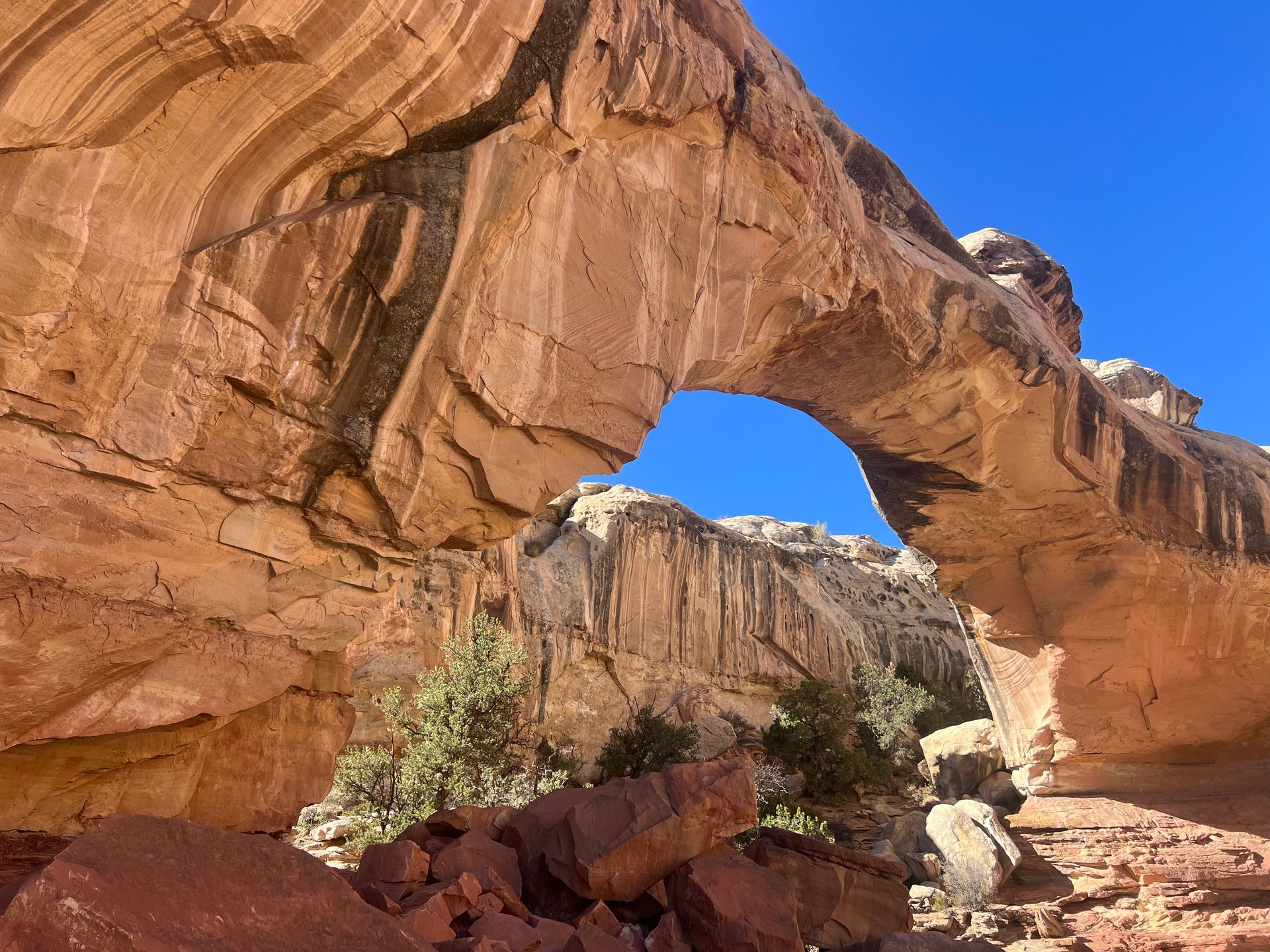 Natural rock archway against a blue sky, with layered sandstone formations.