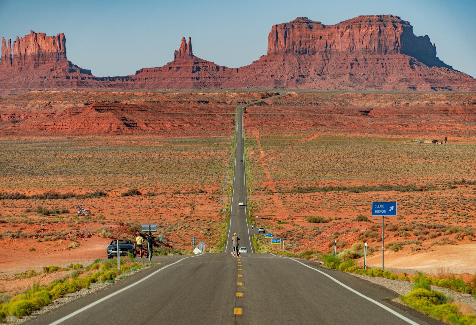 Road in Monument Valley, Utah, leading toward iconic red rock formations under a clear sky.