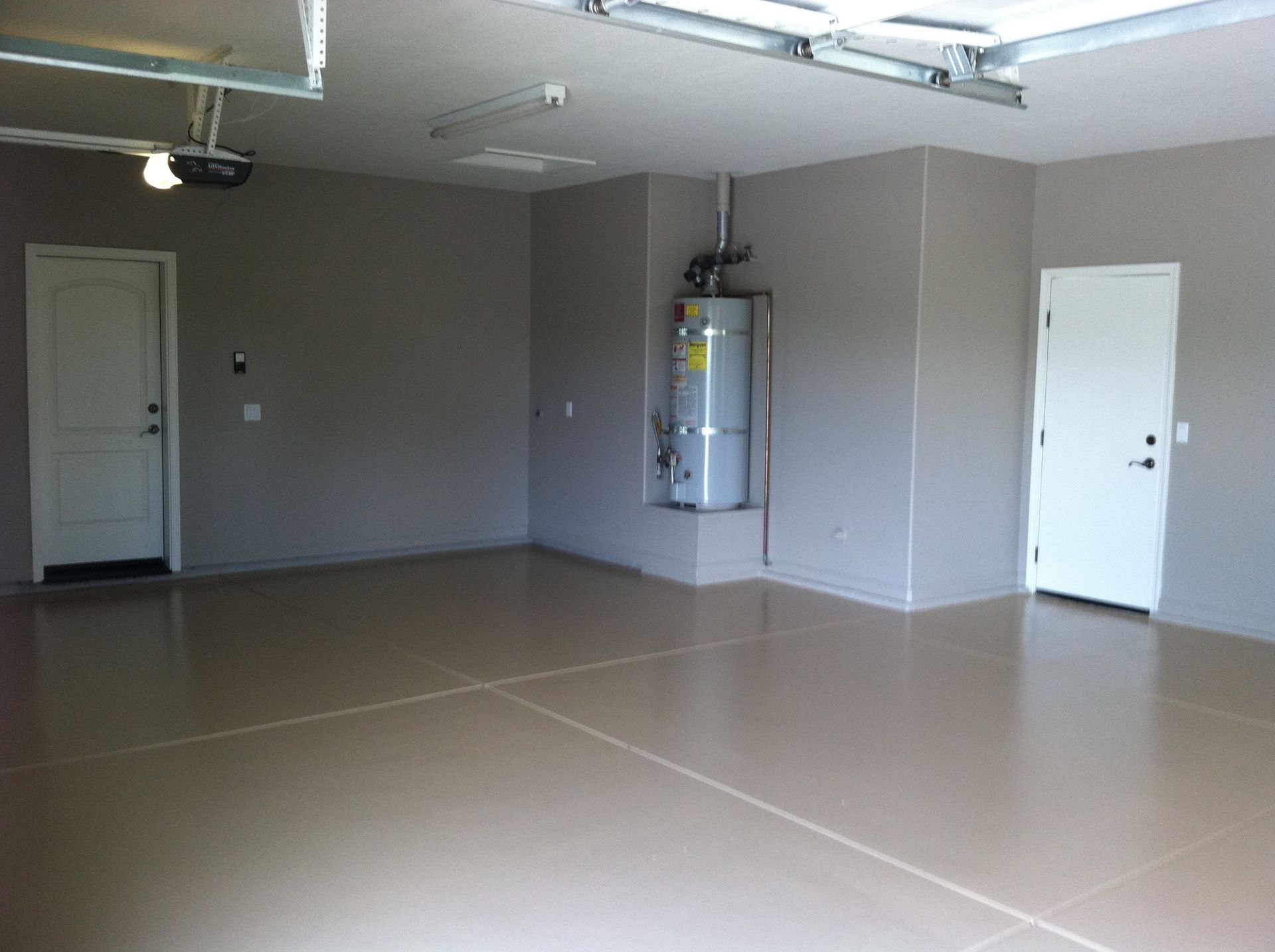 Empty garage with light brown epoxy floor, gray walls, and white doors.