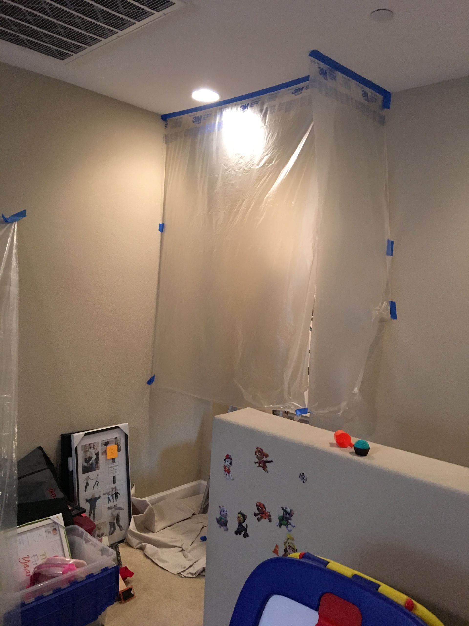 Room with plastic sheeting taped to walls, possibly for renovation.