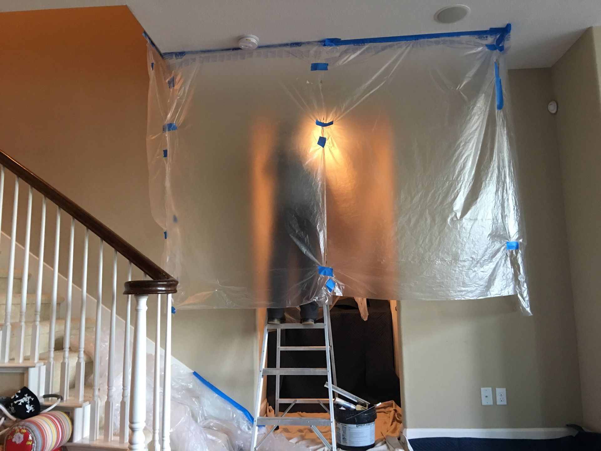 Plastic sheeting taped up, covering a doorway and staircase, protecting the area from painting.
