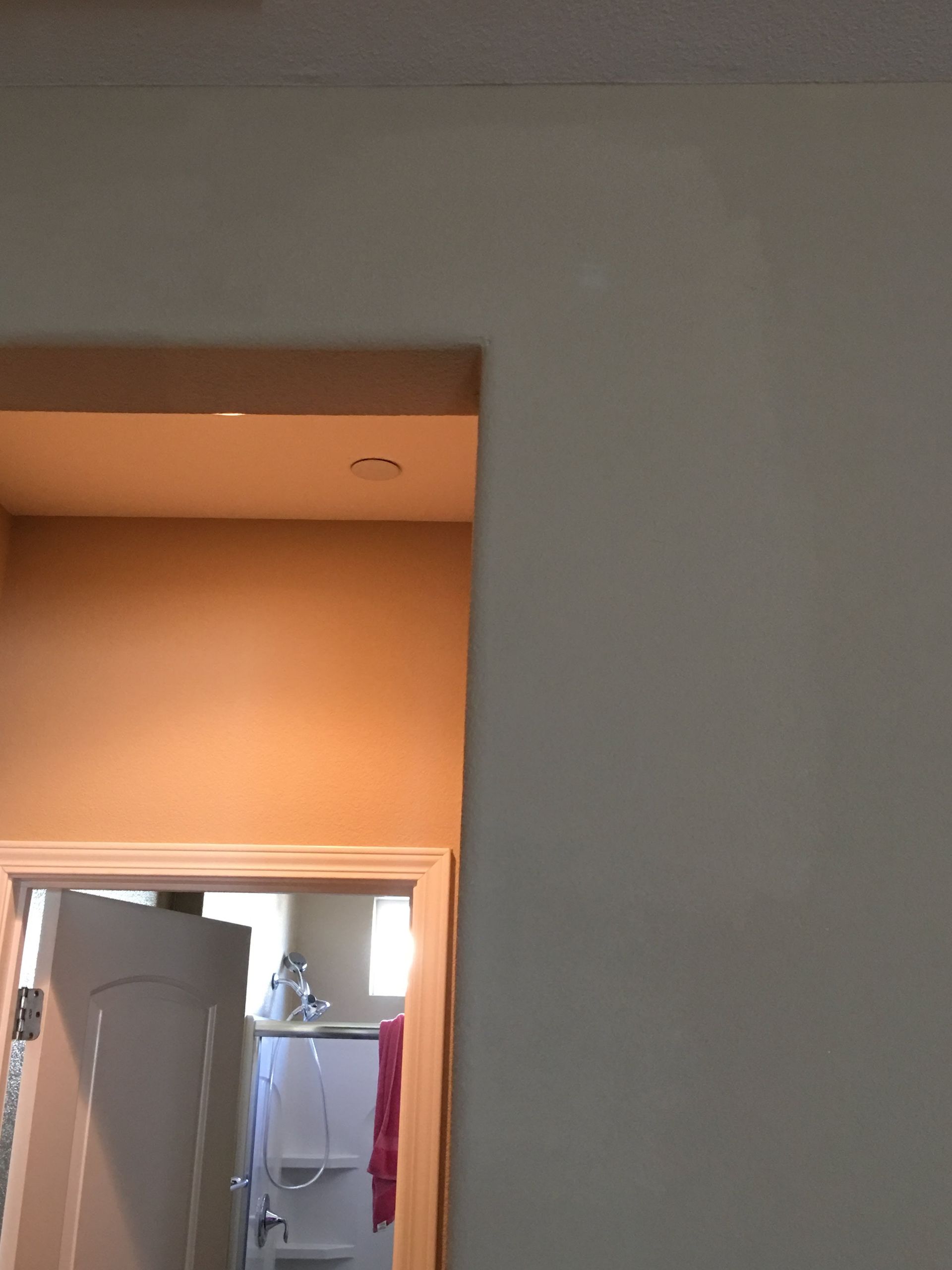 Beige doorway opening into a bathroom. The walls are a light beige, and a red towel hangs in the bathroom.