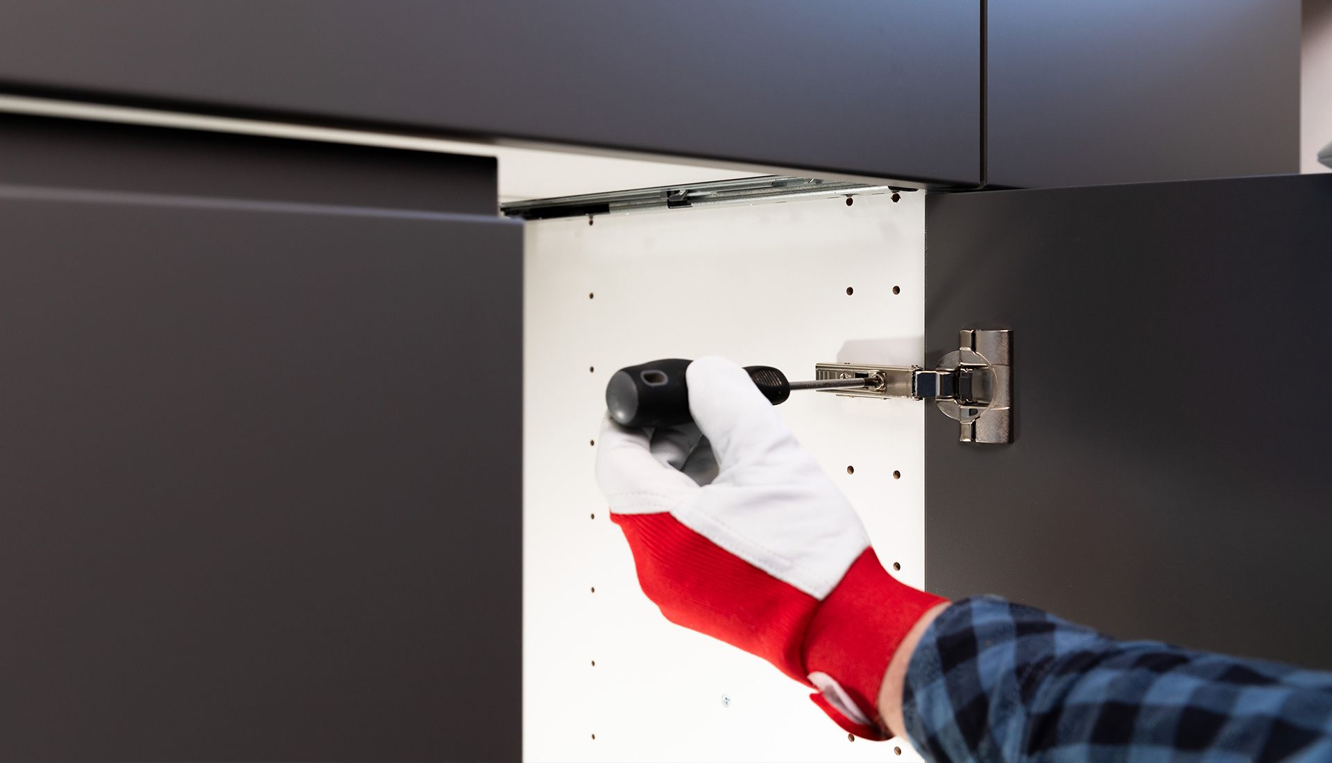 Person taking notes on a clipboard outside a building with a window; wearing a plaid shirt.