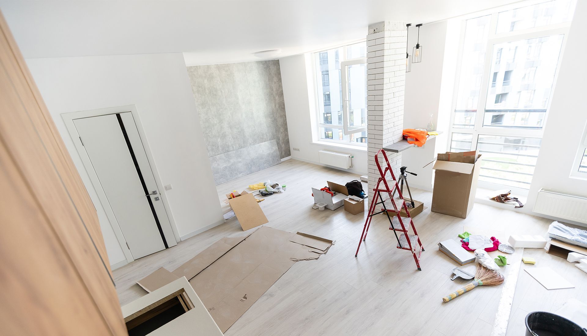 Room undergoing renovation with debris, ladder, and partially exposed wall.