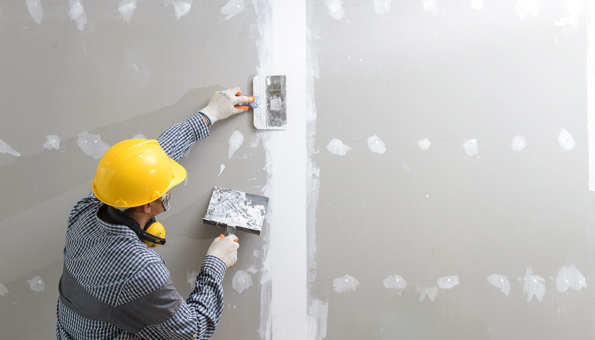 Room under construction with drywall and circular saw on wooden floor.