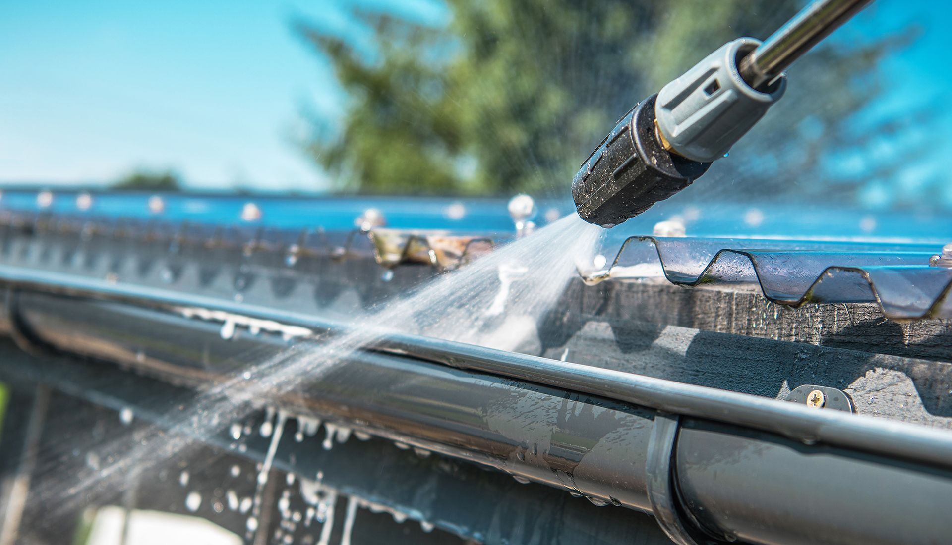 Modern house with brown siding, light tan garage doors, and a concrete driveway under a blue sky.