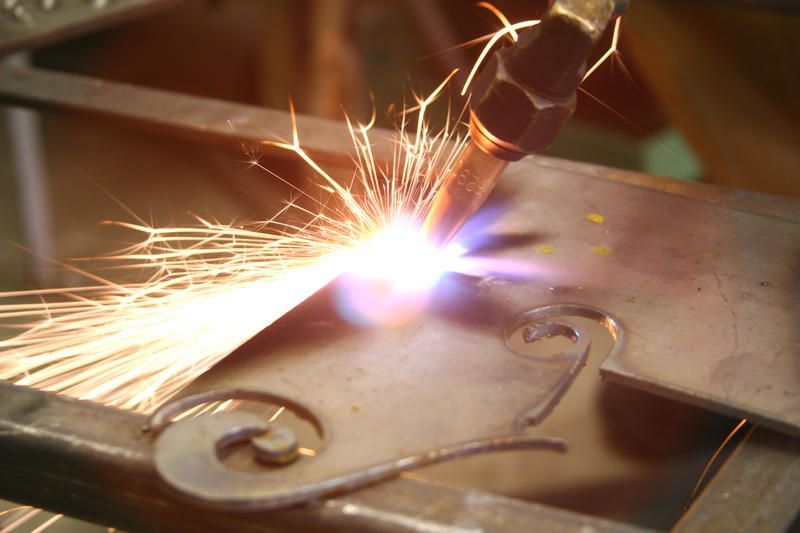 Metal being cut with a torch, producing bright sparks; close-up on the number 2 in a decorative frame.