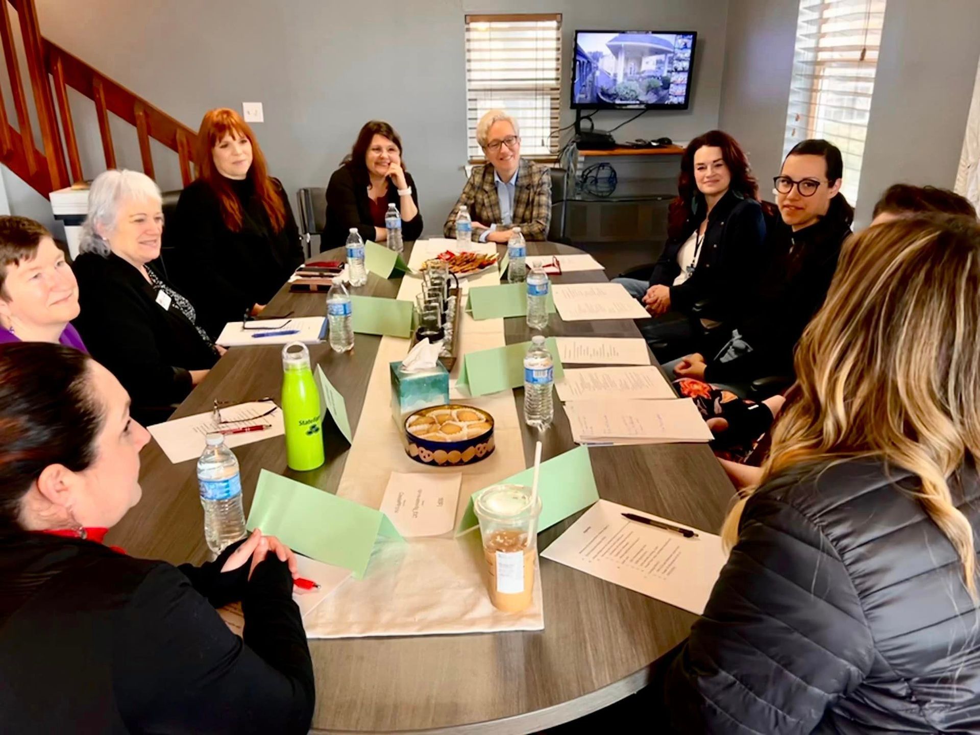 A group of people sitting around a long table, engaged in a discussion.