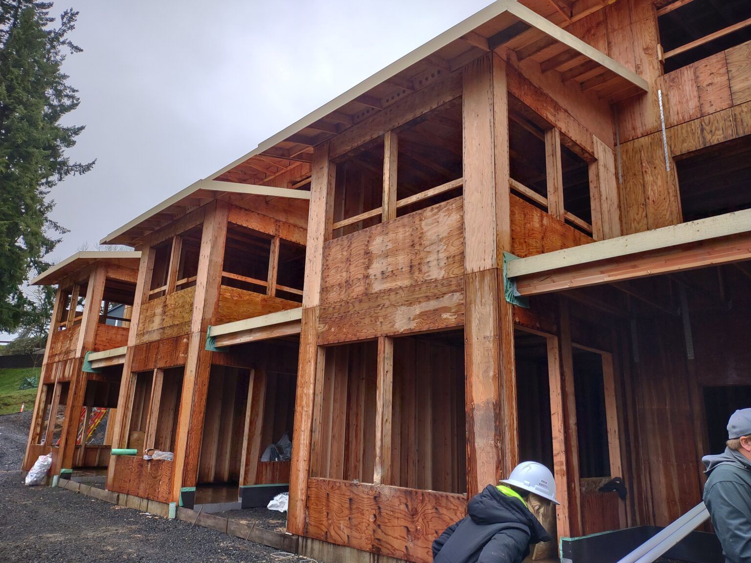 Building under construction with wooden frames and workers visible.