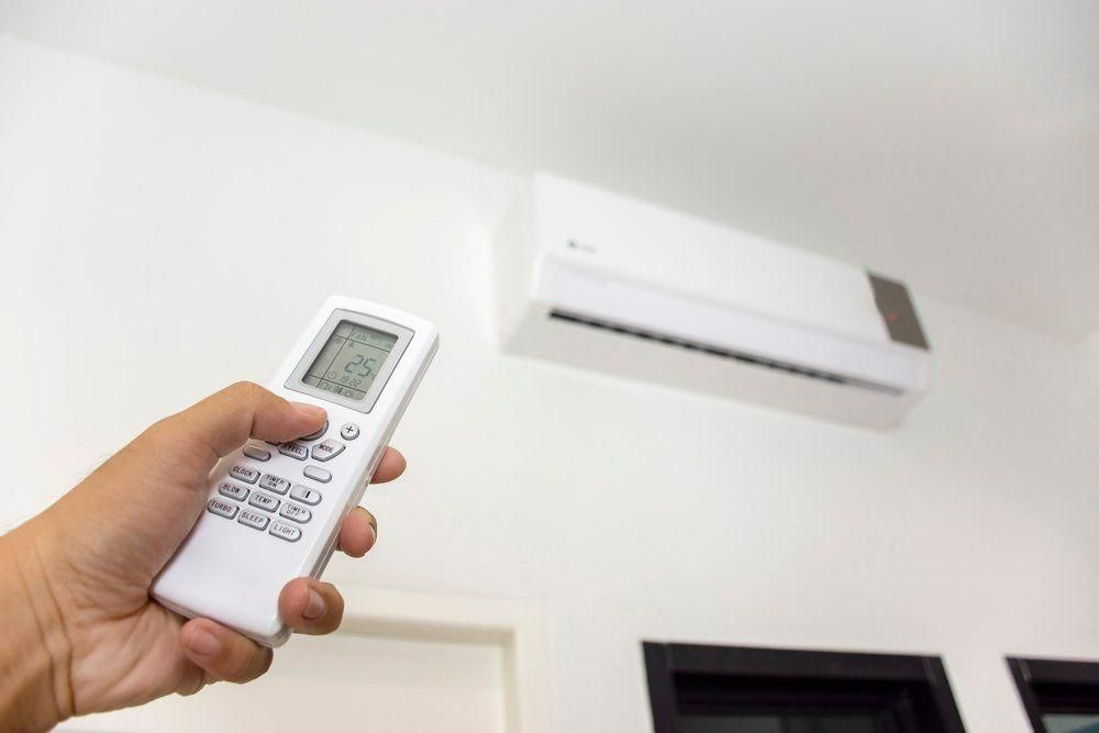 A Person Is Holding A Remote Control In Front Of An Air Conditioner — Jervis Bay Airconditioning In Huskisson, NSW