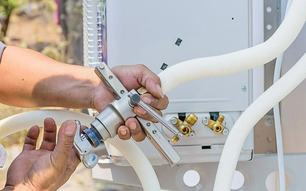 A Man Is Working On An Air Conditioner With A Tool — Jervis Bay Airconditioning In Huskisson, NSW