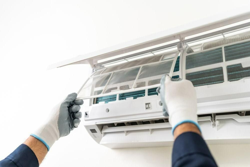 A Person Is Cleaning An Air Conditioner With Gloves On — Jervis Bay Airconditioning In Huskisson, NSW