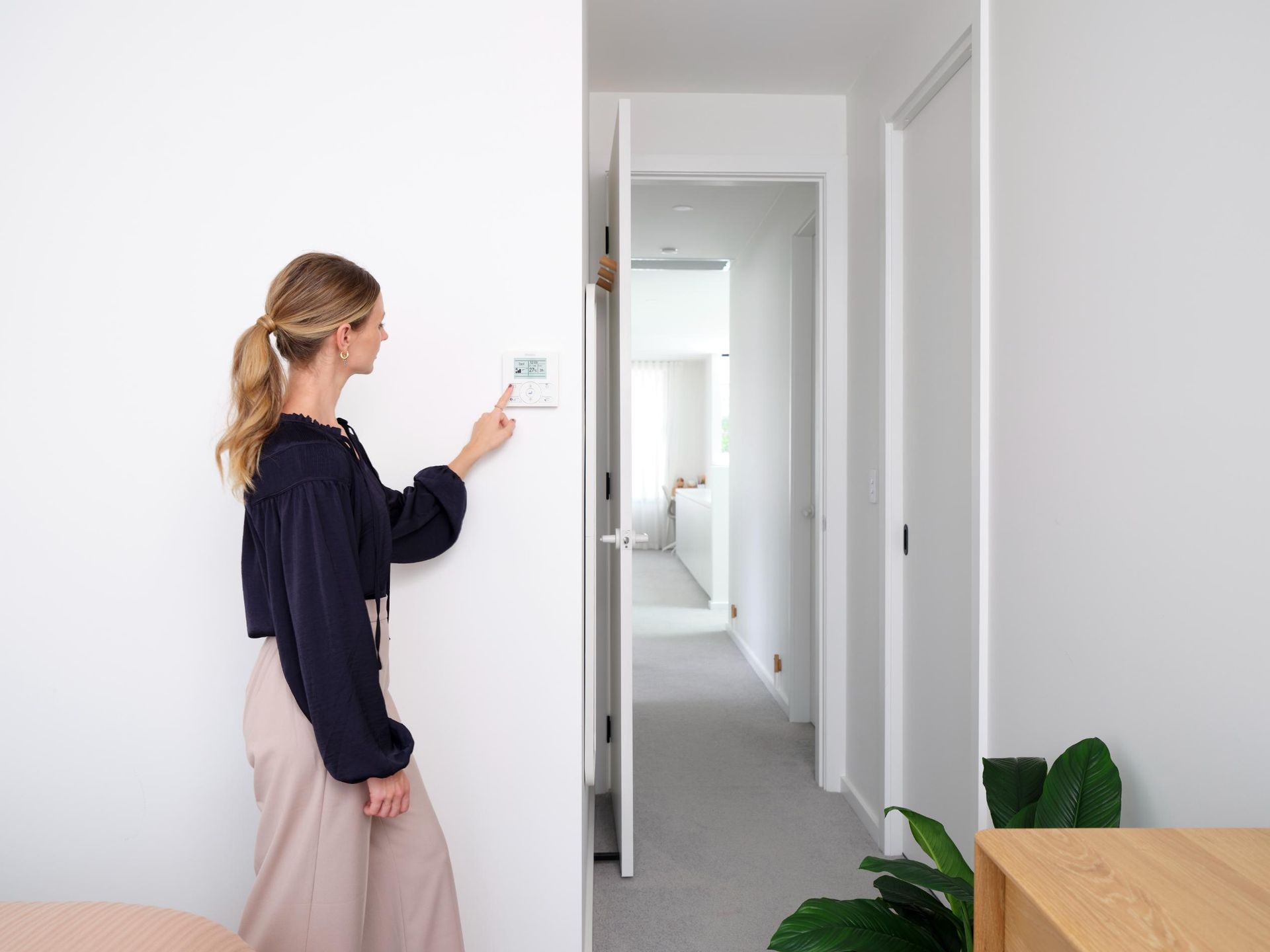 Woman adjusting wall-mounted air conditioning control panel