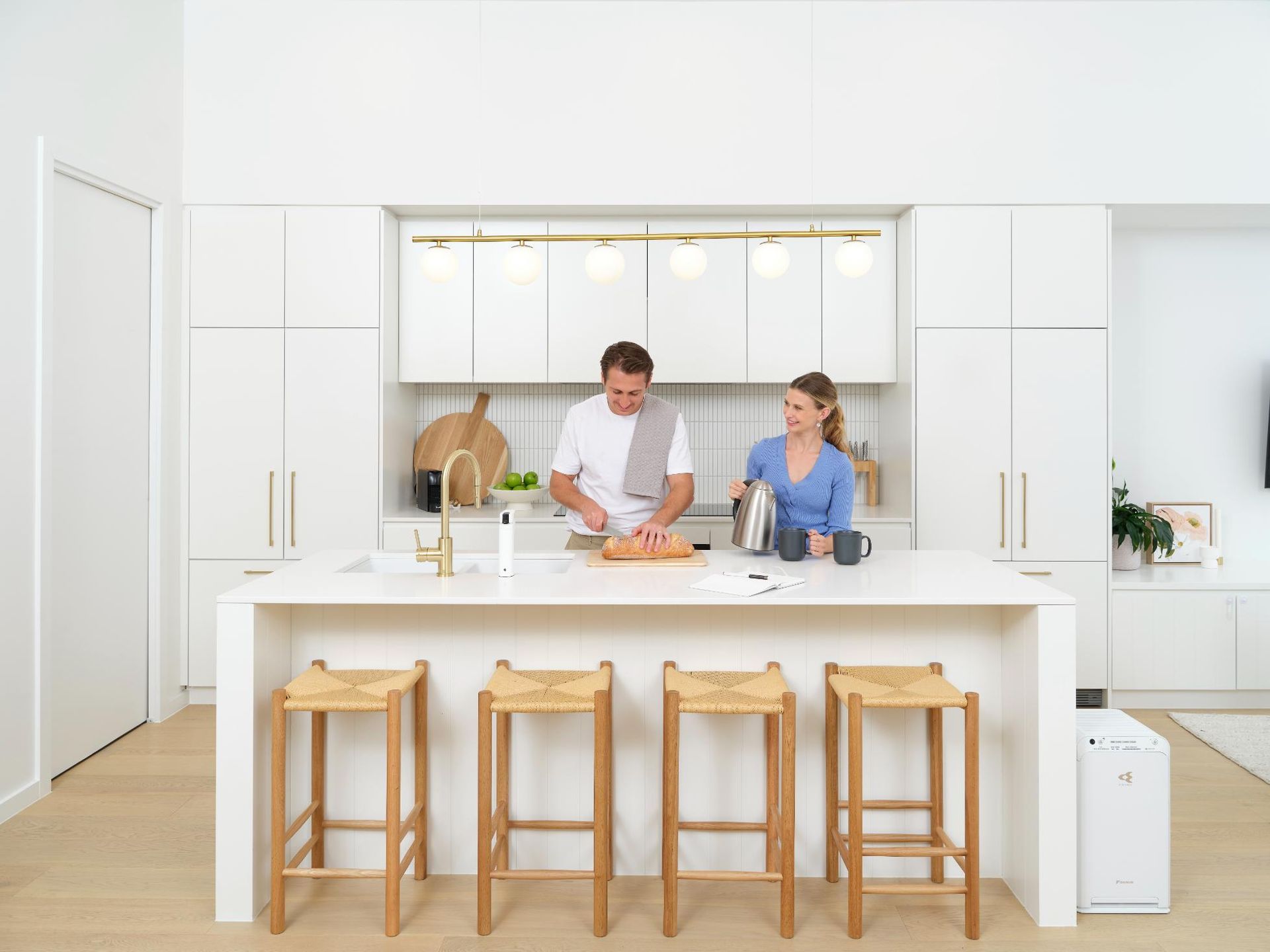 A Man And A Woman Are Standing In A Kitchen Preparing Food — Jervis Bay Airconditioning In Huskisson, NSW