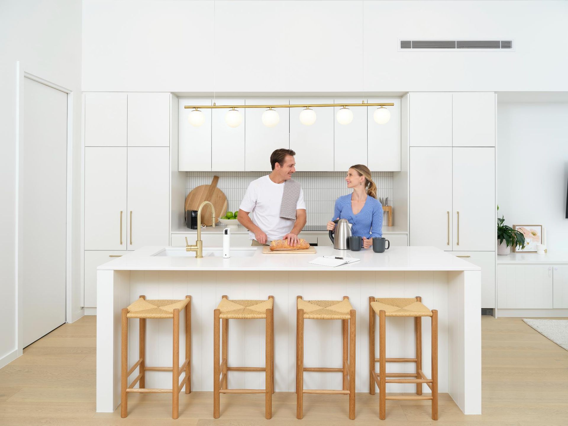 A Man And A Woman Are Standing In A Kitchen Preparing Food — Jervis Bay Airconditioning In Huskisson, NSW