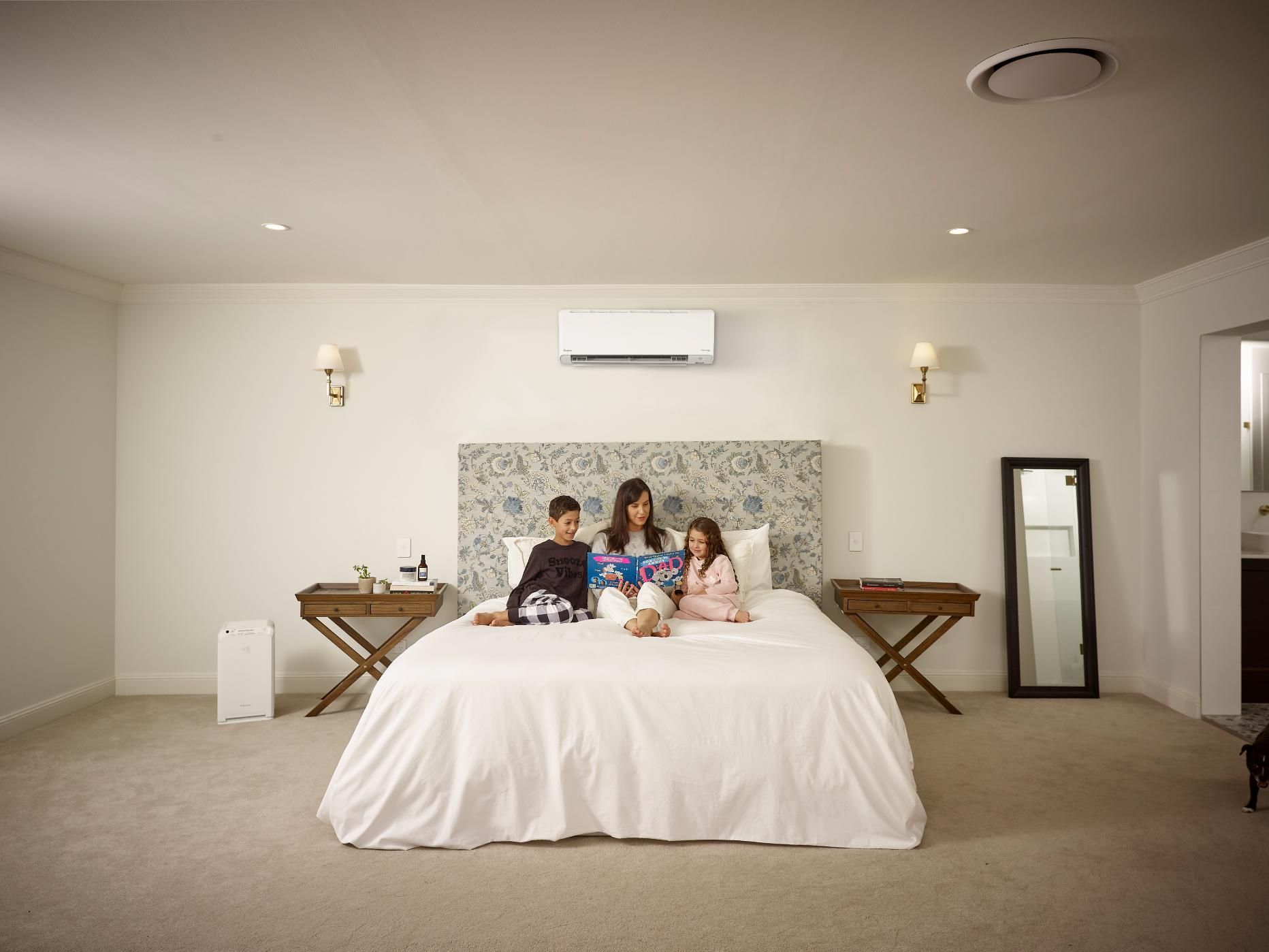 A Family Is Sitting On A Bed In A Bedroom — Jervis Bay Airconditioning In Ulladulla, NSW