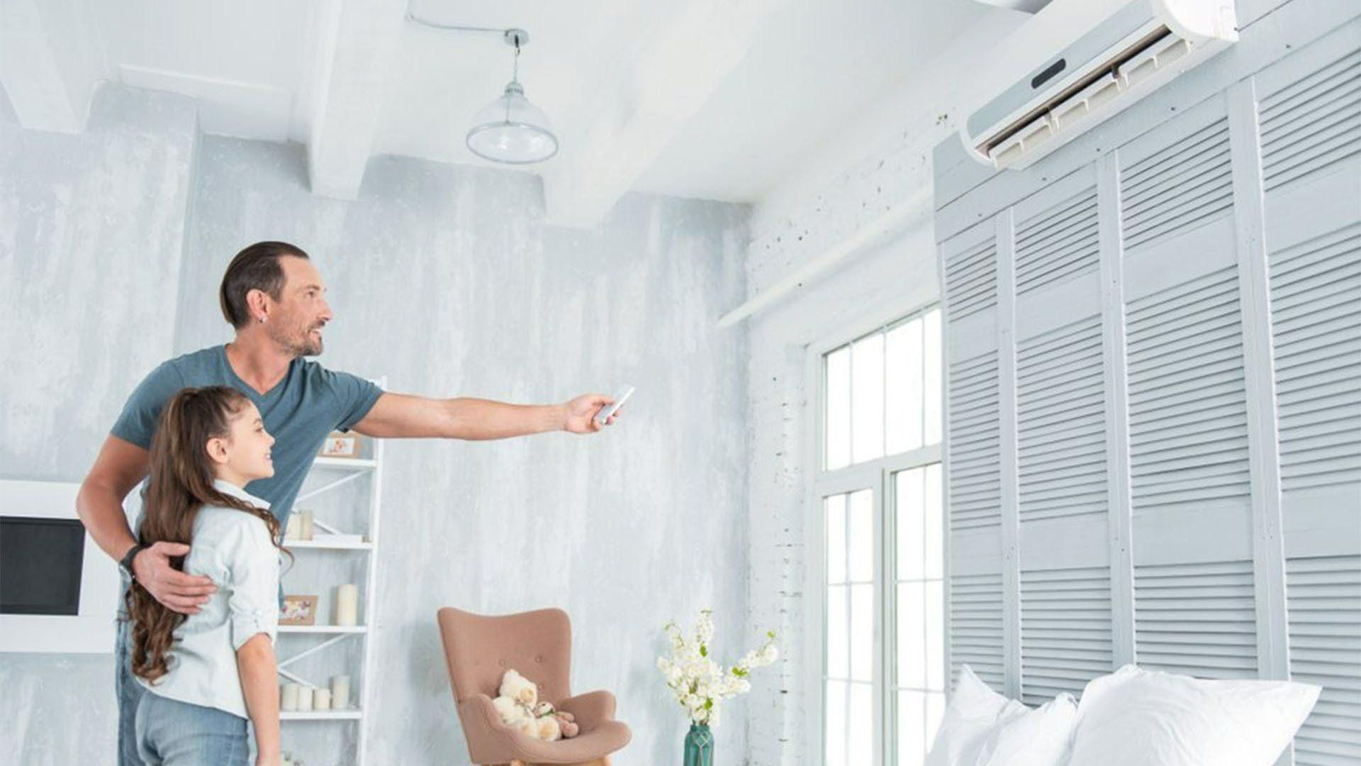 A Man And A Girl Are Standing In A Living Room Looking At An Air Conditioner — Jervis Bay Airconditioning In Berry, NSW