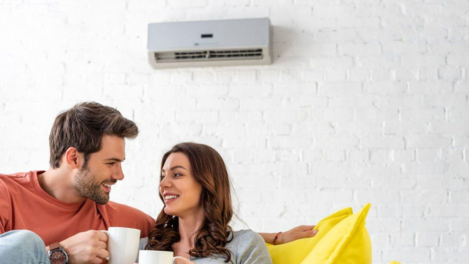 A Man And A Woman Are Sitting On A Bean Bag Chair Drinking Coffee — Jervis Bay Airconditioning In Sussex Inlet, NSW