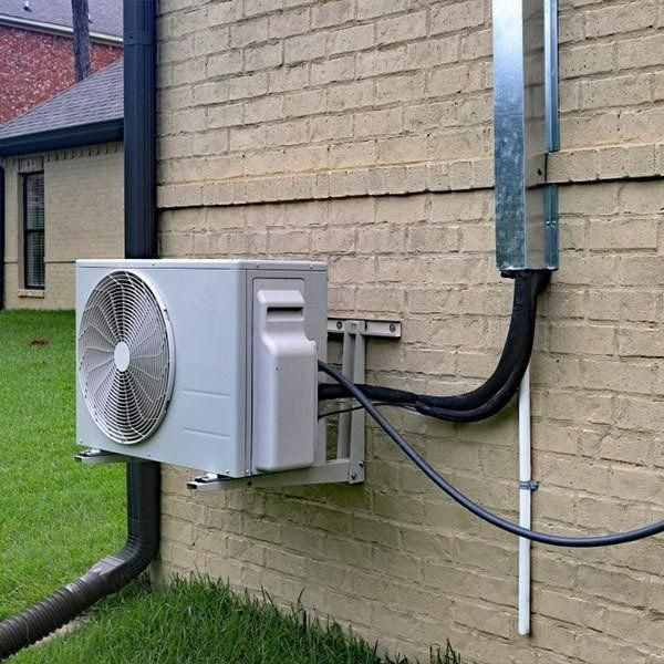 A White Air Conditioner Is Attached To The Side Of A Brick Building — Jervis Bay Airconditioning In Berry, NSW