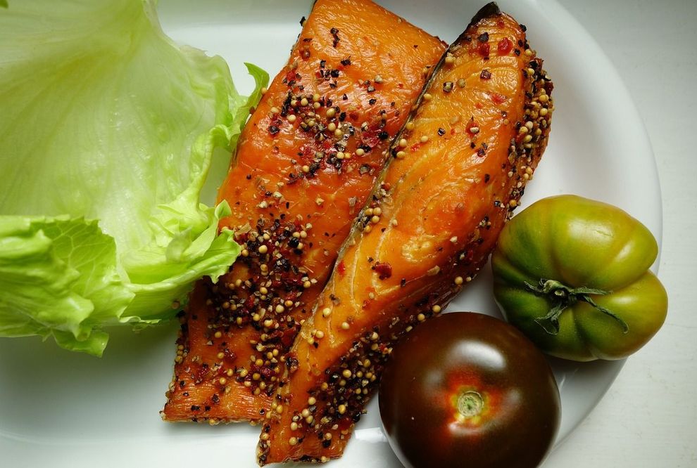 a white plate topped with salmon , lettuce and tomatoes .