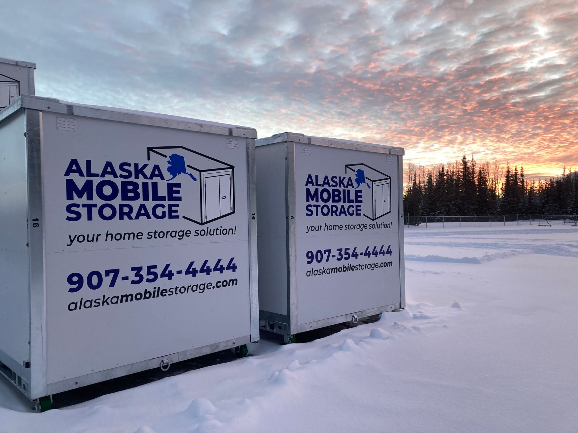 Two alaska mobile storage containers are parked in the snow.