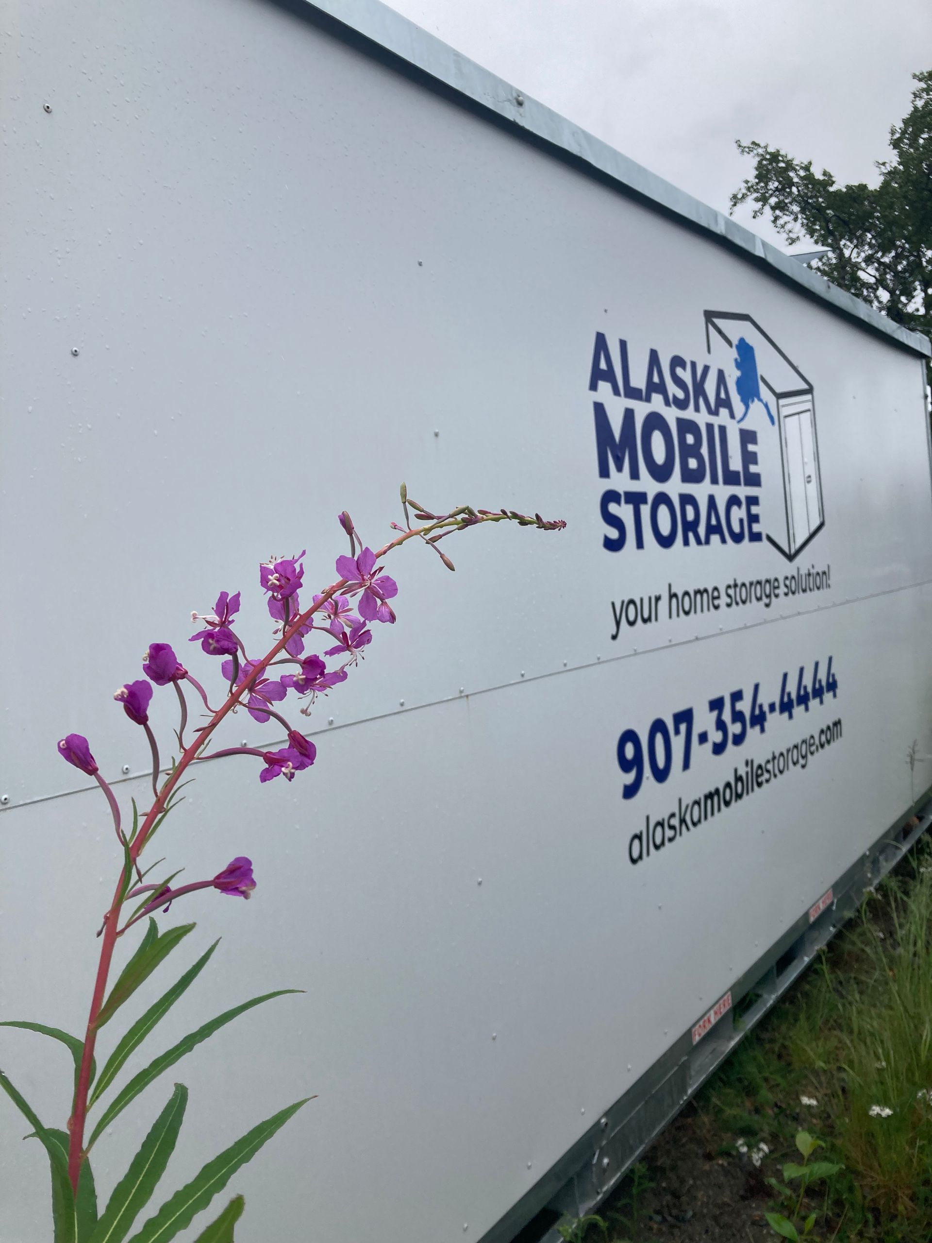 A white alaska mobile storage truck with purple flowers on the side