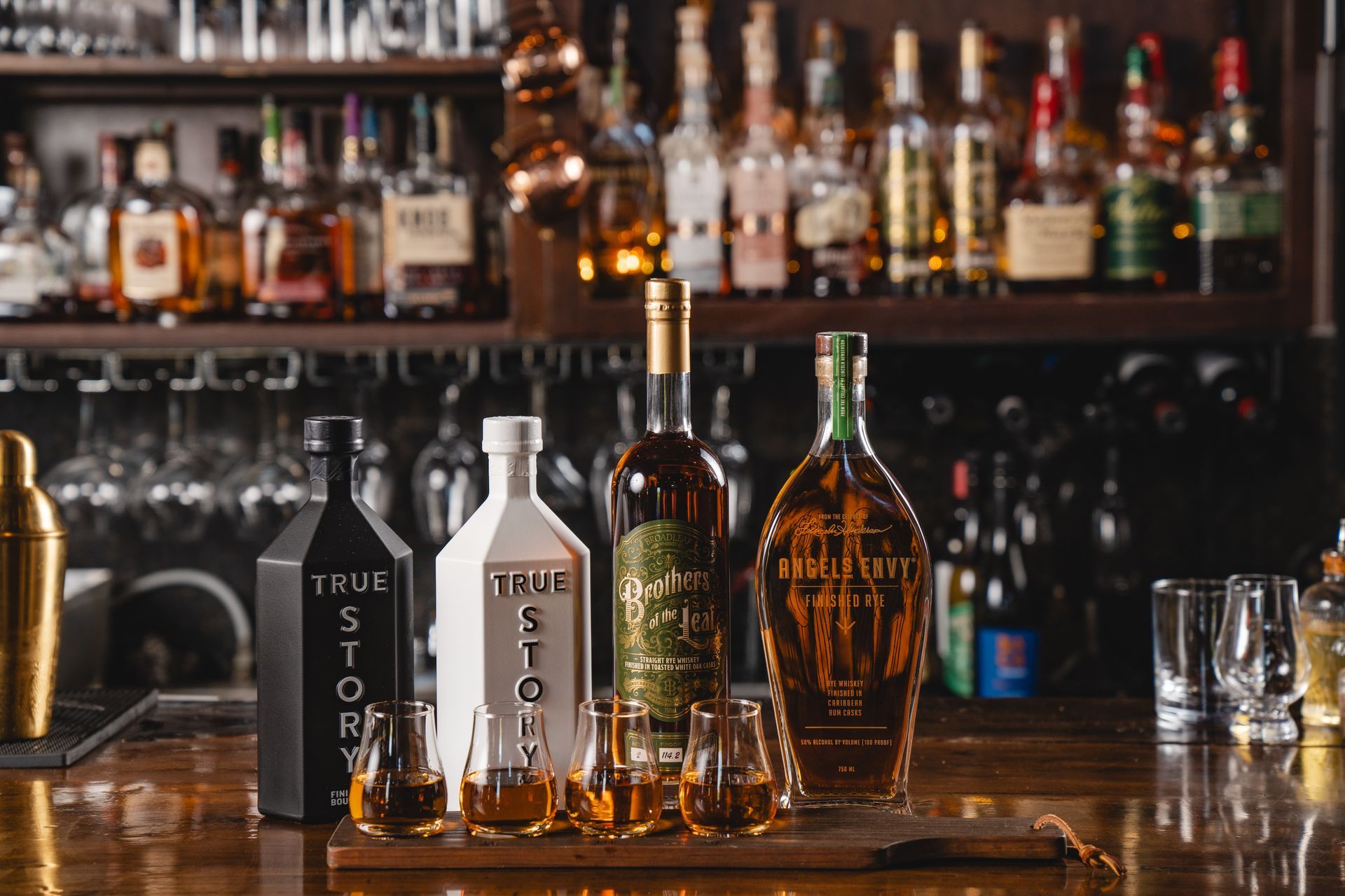 Bar with bottles of whiskey and shot glasses on a wooden surface. Blurred background of shelves with liquor.