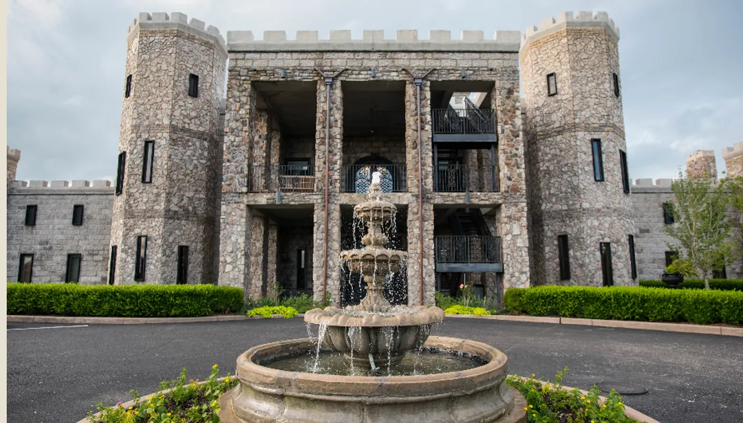 Stone castle with a fountain in front.