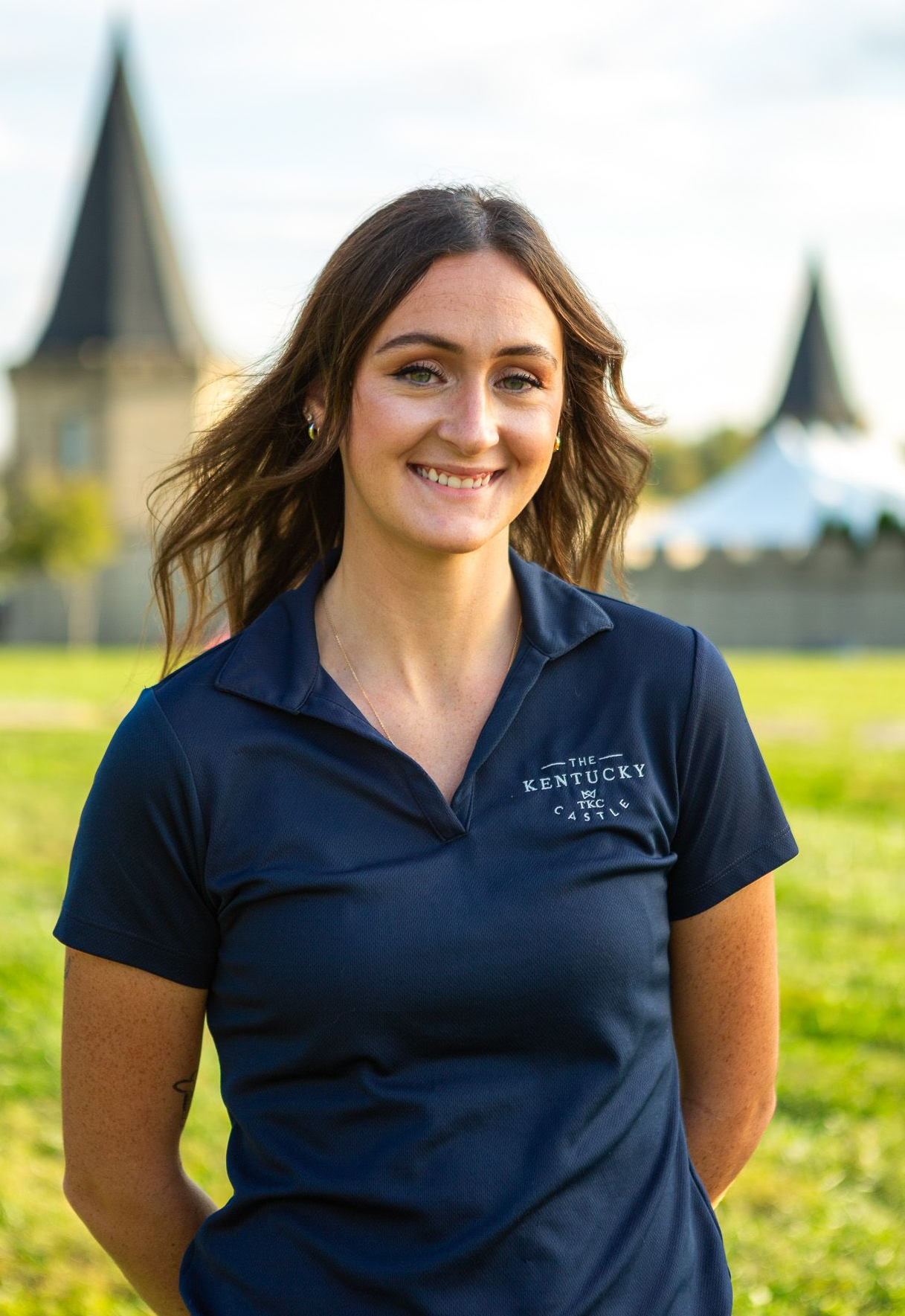 Man in gray suit and blue tie smiles in elegant, blurred interior.
