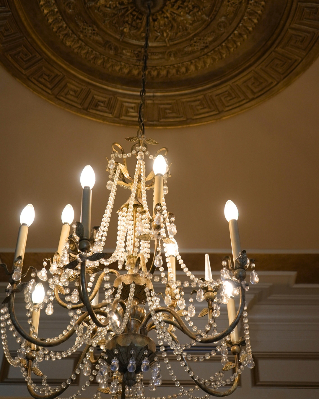 Ornate chandelier hanging from a gold-detailed ceiling.