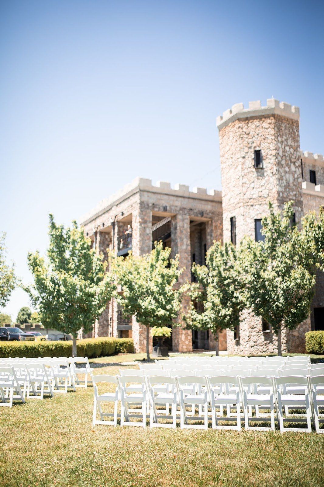 White chairs face a castle for an outdoor event on a sunny day.