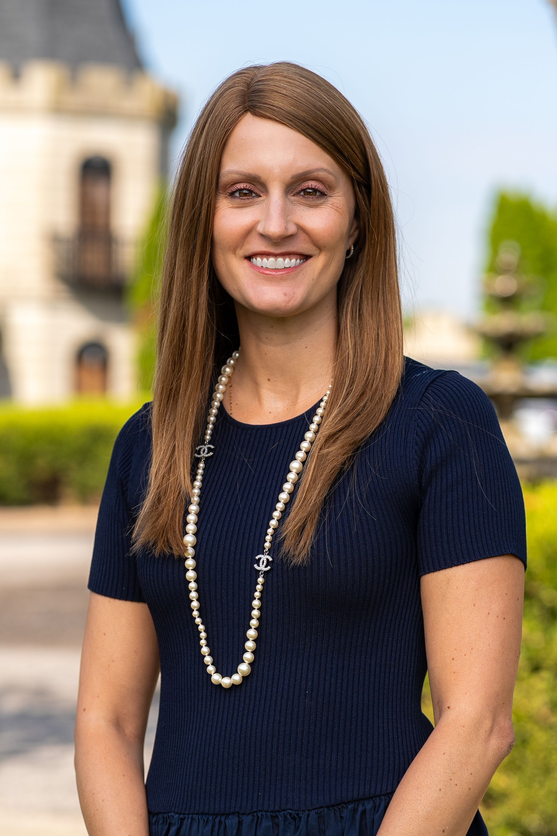 Woman in white blazer smiles in ornate interior.