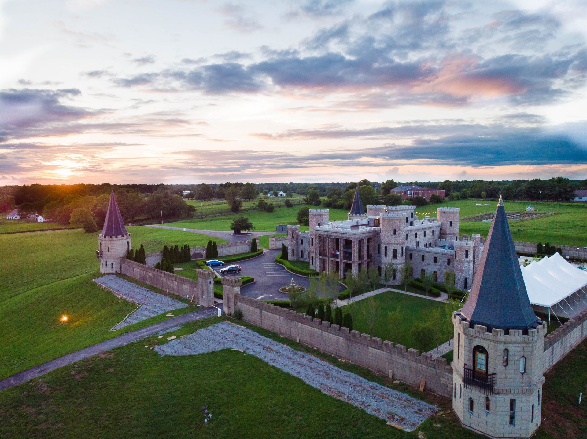 Castle at sunset, with stone walls, towers, and a grassy lawn.