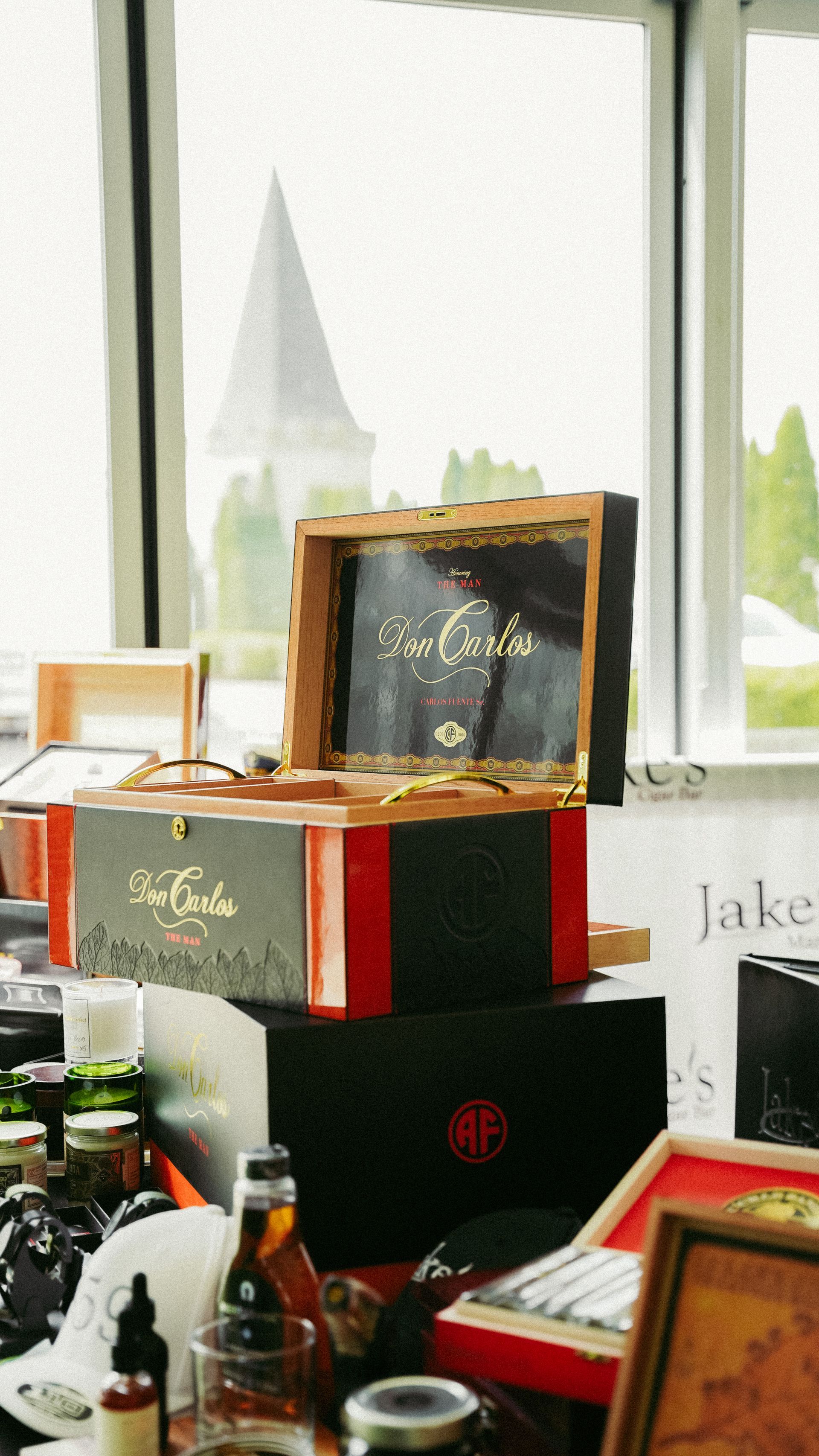Cigar boxes stacked on table with window and church spire in background.