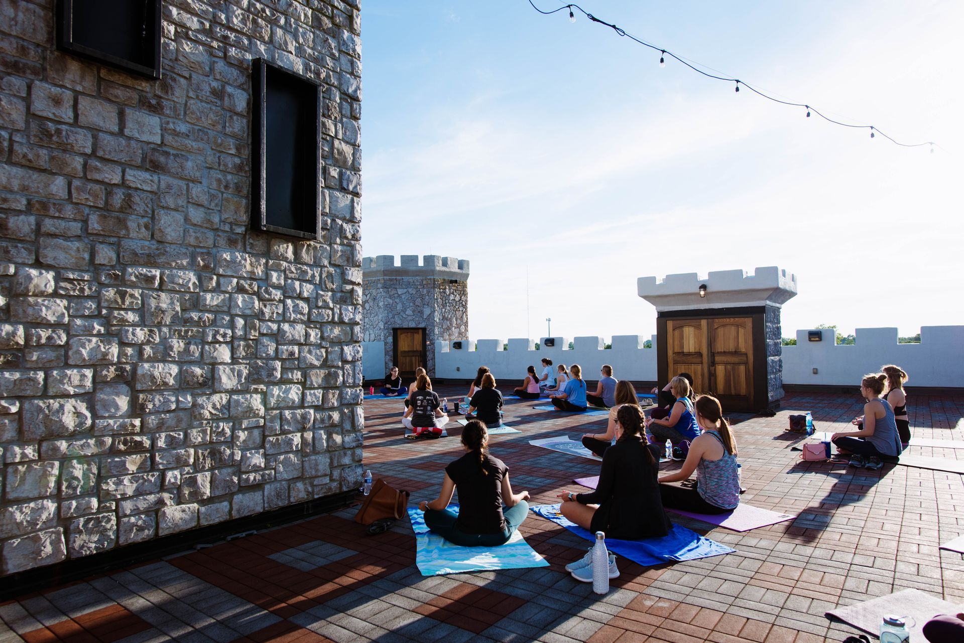 People doing yoga on a castle rooftop in the sun.