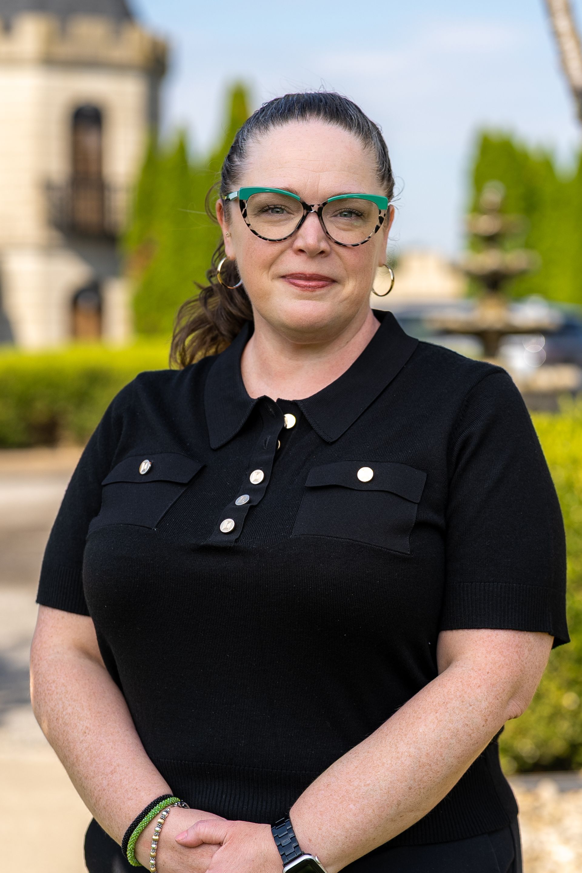 Woman in white blazer smiles in ornate interior.