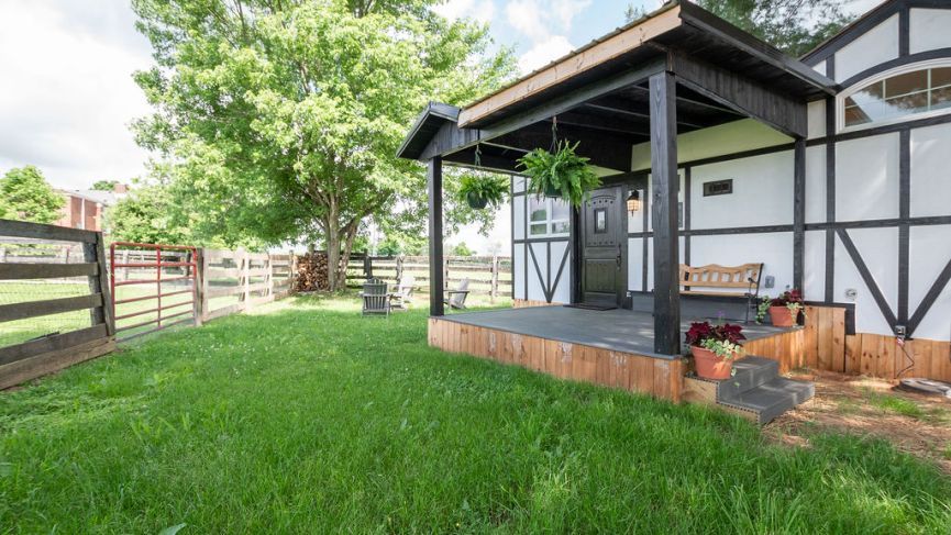 Small Tudor style house with a porch and green lawn.